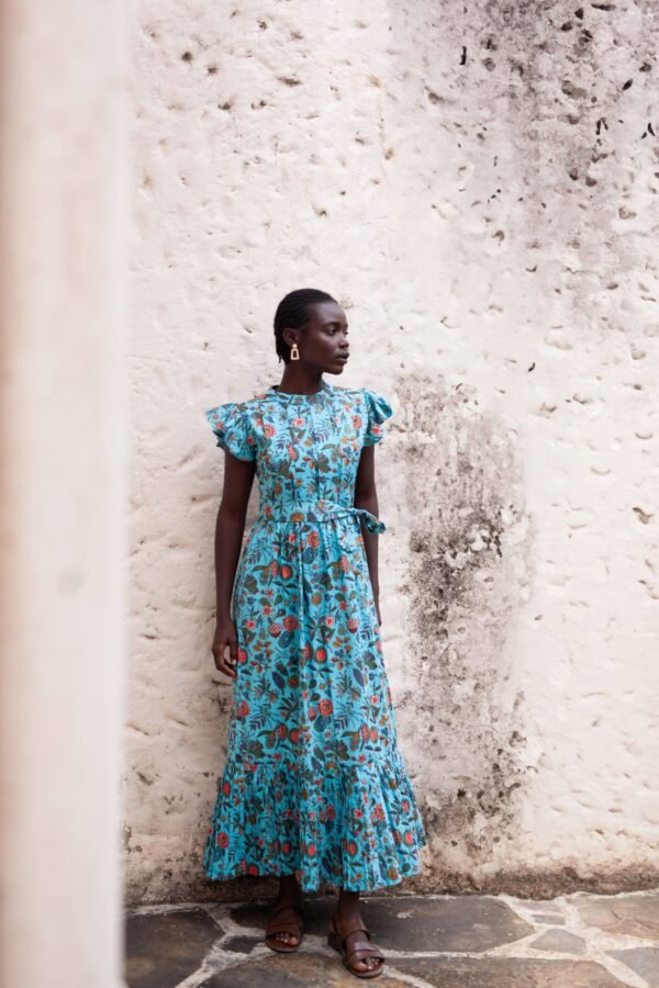 Dress made from hand block printed cotton in soft hues, featuring pleated details, a round neckline, and off-shoulder ruffles. The slim-fitted bodice hugs curves, flowing into a floor-length skirt. Includes a detachable belt and inseam pockets.